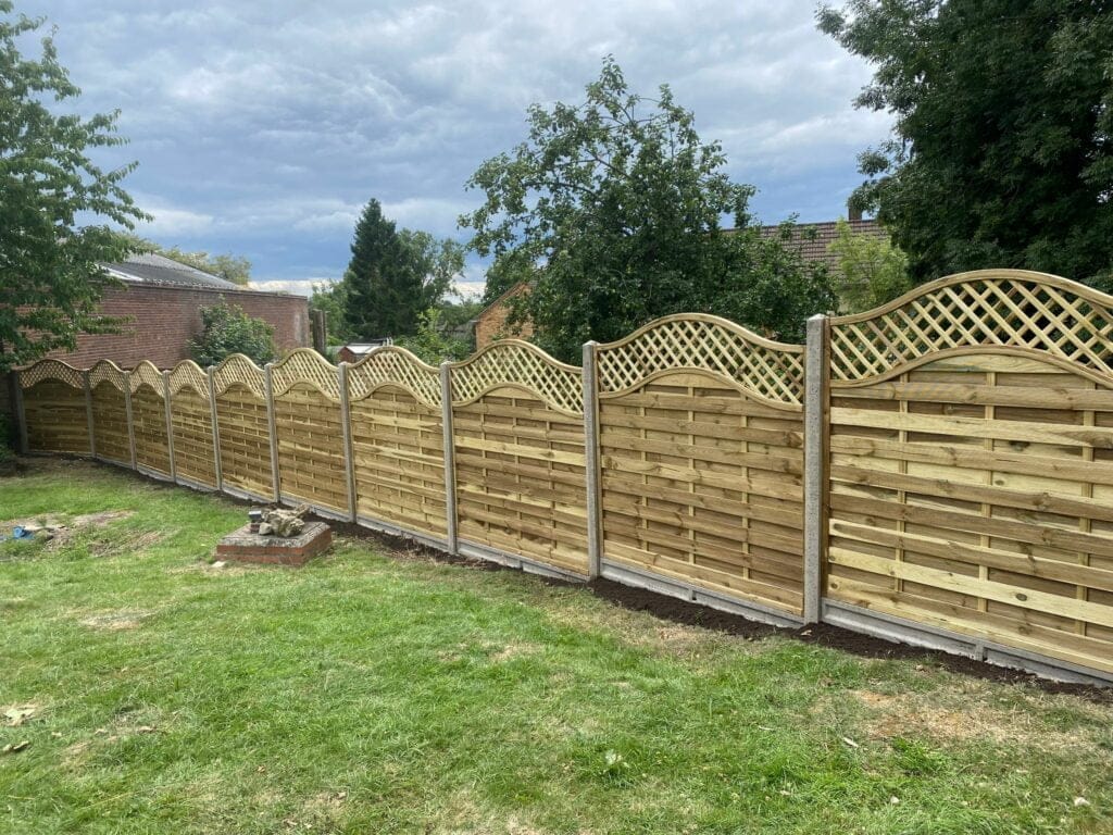 An image showing a cloudy sky which focuses on a row of decorative fence panels recently installed along the grass.