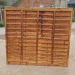 An overlap fence panel standing upright on a concrete path.